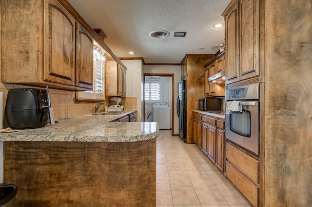 kitchen featuring sink, oven, refrigerator, ornamental molding, and washer / dryer