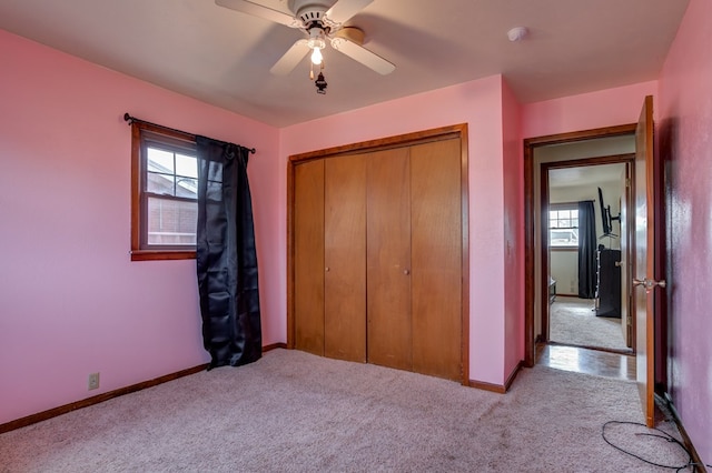 unfurnished bedroom featuring ceiling fan, a closet, light carpet, and multiple windows