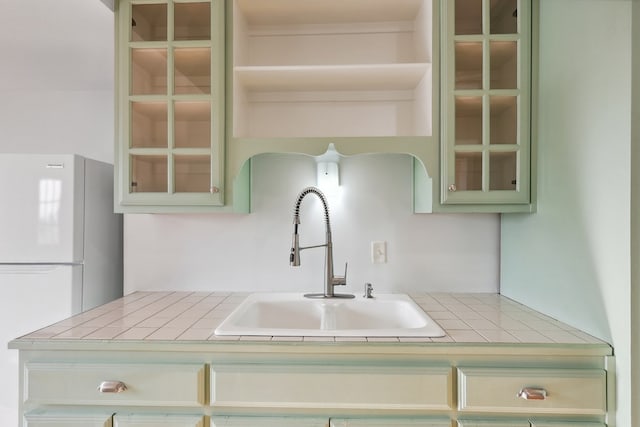 101 N 7th St, Marathon, TX 79842 - kitchen featuring freestanding refrigerator, a sink, glass insert cabinets, and green cabinets