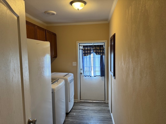 laundry room with cabinet space, crown molding, dark wood-style floors, and washer and clothes dryer