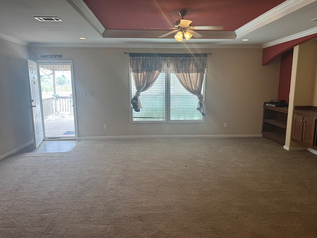 unfurnished living room with ceiling fan, baseboards, ornamental molding, carpet, and a tray ceiling