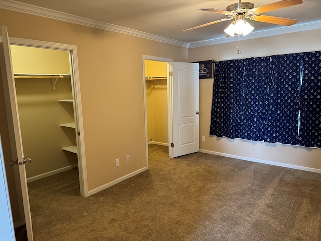 unfurnished bedroom with carpet floors, ornamental molding, baseboards, and a walk in closet