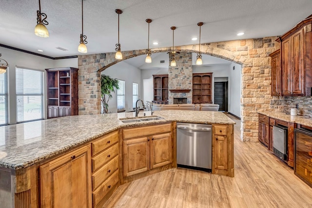 kitchen with sink, hanging light fixtures, light wood-type flooring, a textured ceiling, and dishwasher