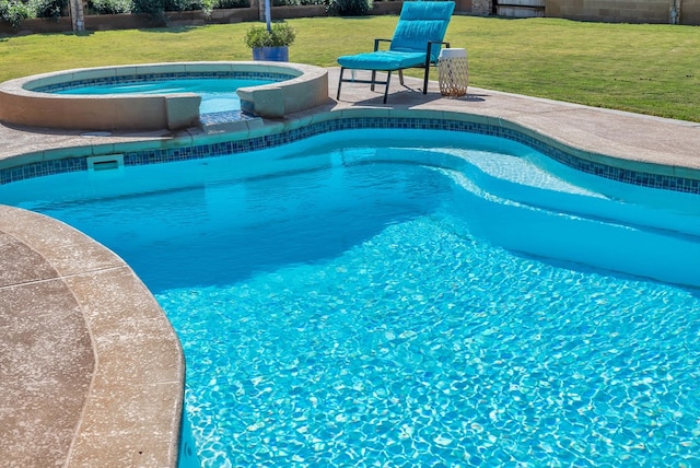 view of pool with a lawn and an in ground hot tub