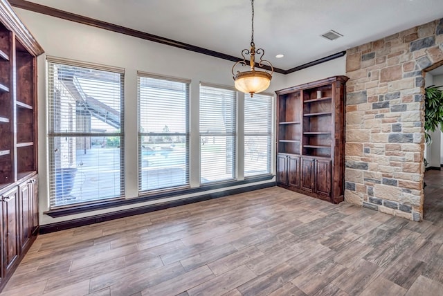 unfurnished dining area featuring hardwood / wood-style flooring and crown molding