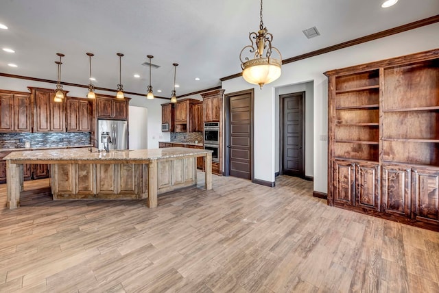 kitchen with appliances with stainless steel finishes, a center island with sink, a kitchen breakfast bar, and decorative light fixtures