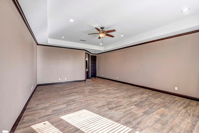 unfurnished room with ceiling fan, a raised ceiling, and light wood-type flooring