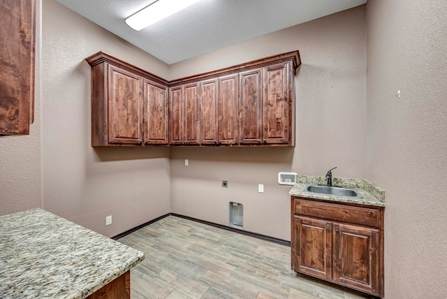 clothes washing area featuring sink, cabinets, light wood-type flooring, hookup for a washing machine, and electric dryer hookup