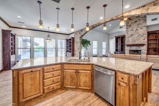 kitchen featuring sink, hanging light fixtures, stainless steel dishwasher, light stone counters, and a center island with sink