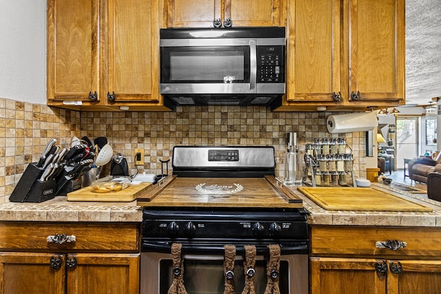 1703 Hemphill Ave, Odessa, TX 79763 - kitchen featuring stainless steel appliances, decorative backsplash, brown cabinets, and light countertops