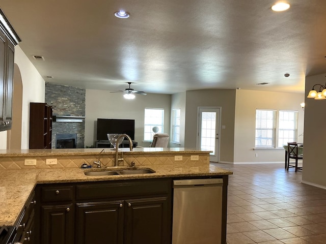 2804 Anice St, Odessa, TX 79762 - kitchen with stainless steel dishwasher, open floor plan, a sink, light tile patterned floors, and a fireplace