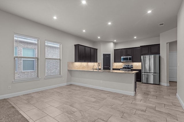 8901 Ratliff Ridge Ave, Odessa, TX 79765 - kitchen featuring appliances with stainless steel finishes, backsplash, recessed lighting, a peninsula, and light stone counters