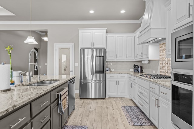 8620 Rutland Dr, Odessa, TX 79765 - kitchen with appliances with stainless steel finishes, custom range hood, white cabinets, backsplash, and light wood finished floors