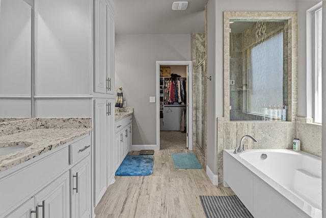 8620 Rutland Dr, Odessa, TX 79765 - full bath featuring a shower stall, vanity, a garden tub, wood finished floors, and a walk in closet