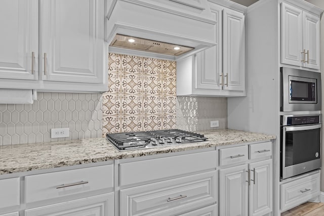 8620 Rutland Dr, Odessa, TX 79765 - kitchen with appliances with stainless steel finishes, white cabinets, decorative backsplash, and premium range hood