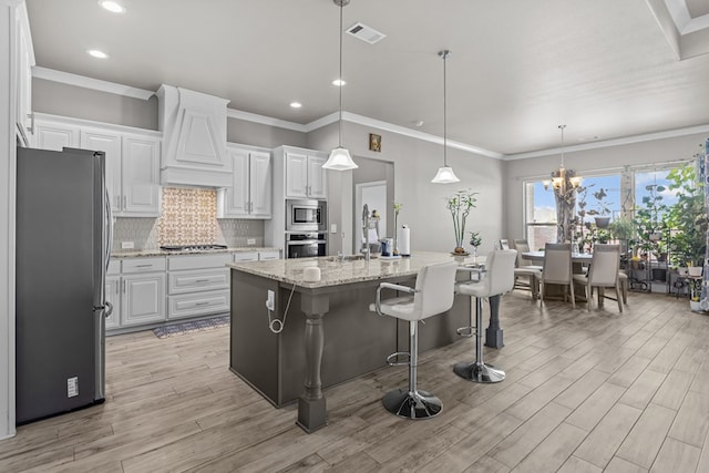 8620 Rutland Dr, Odessa, TX 79765 - kitchen with appliances with stainless steel finishes, custom range hood, backsplash, white cabinetry, and light wood finished floors