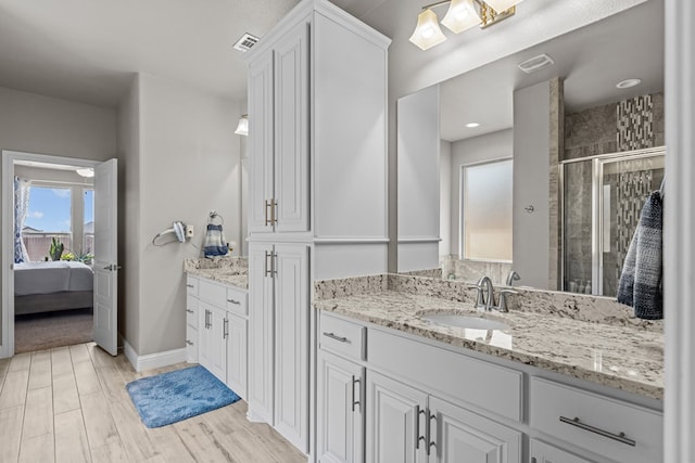 8620 Rutland Dr, Odessa, TX 79765 - ensuite bathroom with a stall shower, two vanities, and wood finished floors