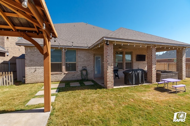 back of house with a lawn, brick siding, a fenced backyard, a patio, and a shingled roof