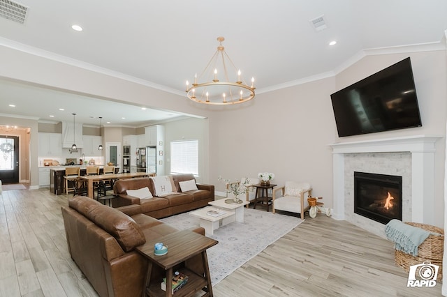 living room featuring visible vents, a glass covered fireplace, an inviting chandelier, and light wood finished floors