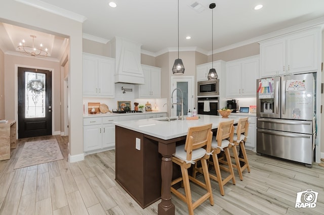 kitchen with appliances with stainless steel finishes, a sink, light countertops, visible vents, and ornamental molding