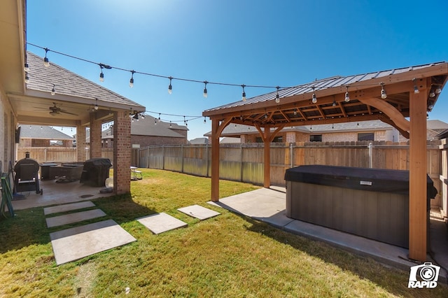 view of yard with a hot tub, a gazebo, a fenced backyard, and a patio area