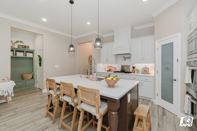 kitchen featuring gas cooktop, light countertops, white cabinets, and premium range hood