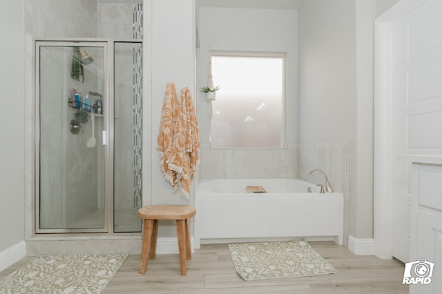 bathroom with baseboards, a stall shower, and a bath