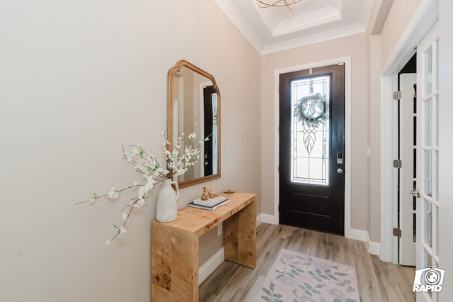 entryway with crown molding, baseboards, a tray ceiling, and light wood finished floors