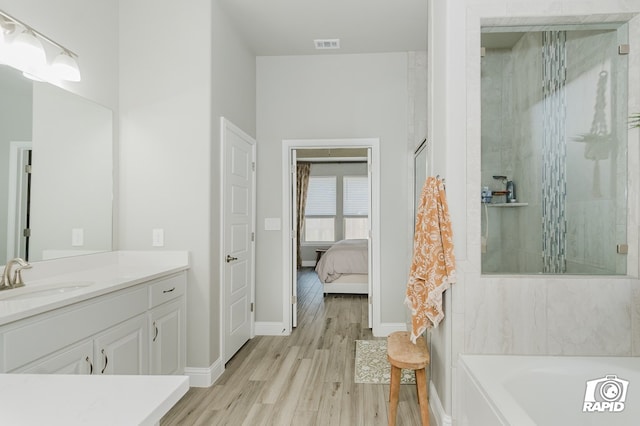 bathroom featuring vanity, a shower with shower door, wood finished floors, and visible vents