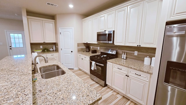 3630 El Cajon Ave, Odessa, TX 79765 - kitchen with appliances with stainless steel finishes, a sink, decorative backsplash, white cabinets, and light stone counters
