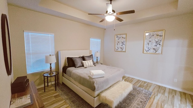 3630 El Cajon Ave, Odessa, TX 79765 - bedroom with light wood-type flooring, baseboards, a tray ceiling, and a ceiling fan