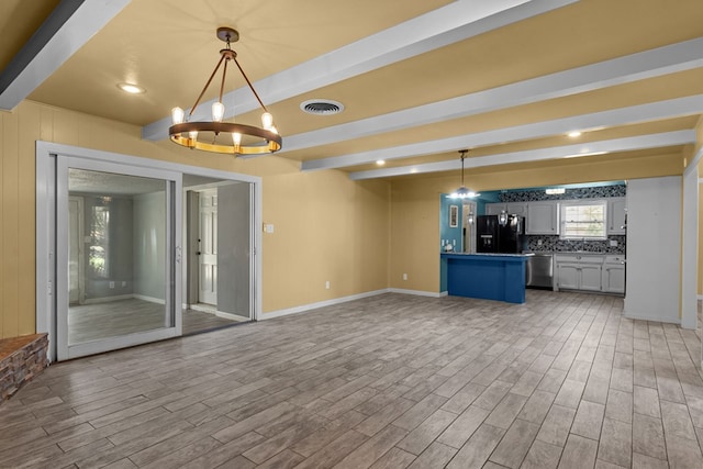 2900 E 21st St, Odessa, TX 79761 - unfurnished living room with beam ceiling, baseboards, a chandelier, and wood finished floors