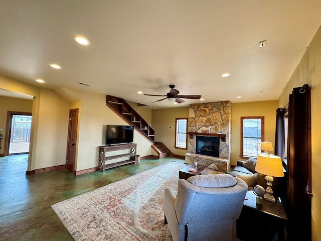 living room with ceiling fan and a stone fireplace