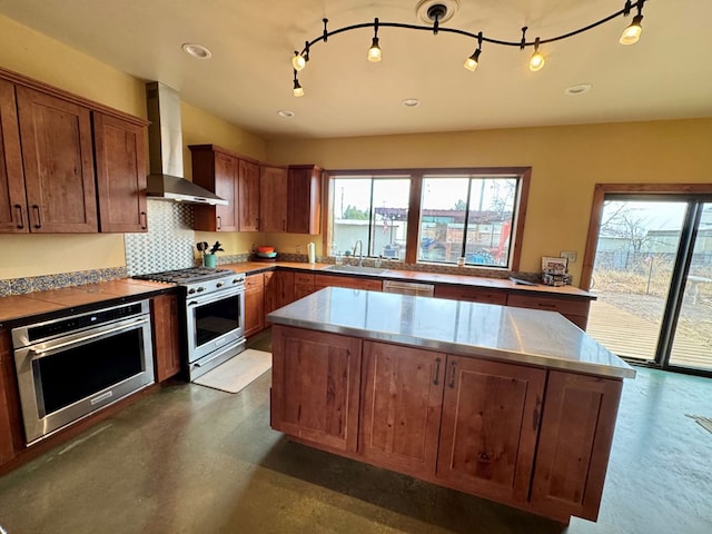 kitchen featuring wall chimney exhaust hood, sink, appliances with stainless steel finishes, a kitchen island, and backsplash