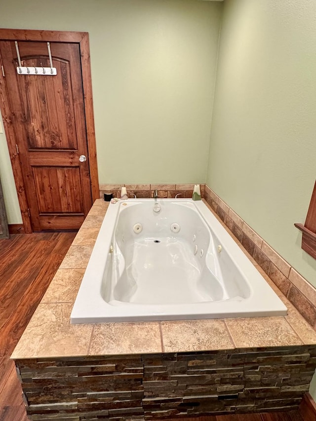 bathroom with tiled tub and hardwood / wood-style floors