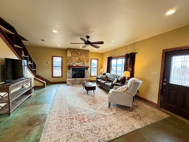 living room with a stone fireplace and ceiling fan