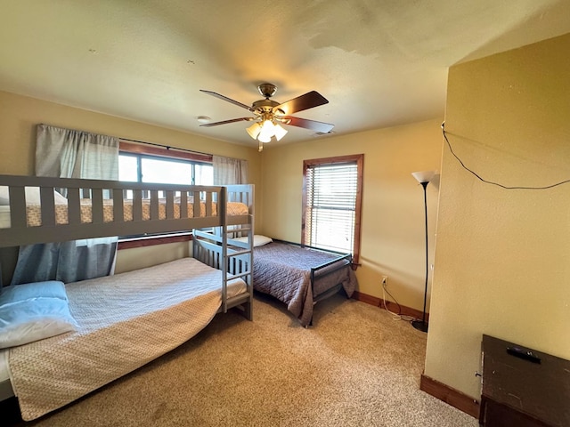 bedroom with ceiling fan, light colored carpet, and multiple windows