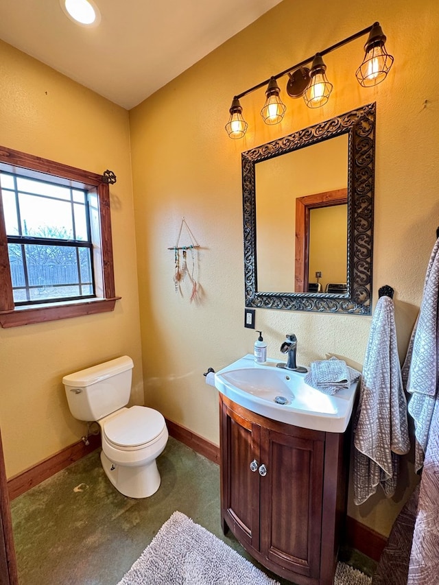 bathroom with concrete flooring, vanity, and toilet