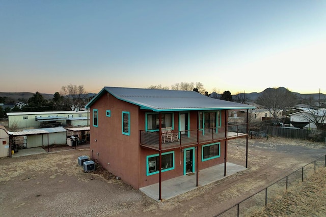 back house at dusk with a mountain view and a patio area