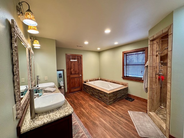 bathroom with hardwood / wood-style flooring, plus walk in shower, and vanity