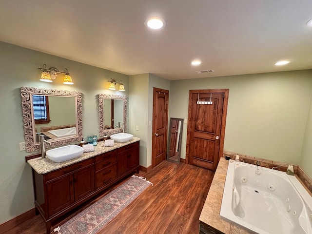 bathroom with vanity, hardwood / wood-style floors, and tiled tub