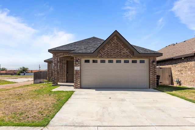 2208 Boise Dr, Odessa, TX 79762 - french country style house with brick siding, driveway, an attached garage, and a shingled roof