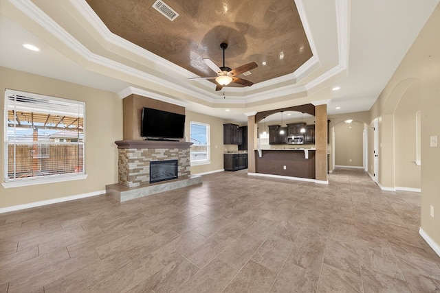 14 Da Vinci Ct, Odessa, TX 79765 - unfurnished living room with a tray ceiling, arched walkways, ornamental molding, a ceiling fan, and a fireplace