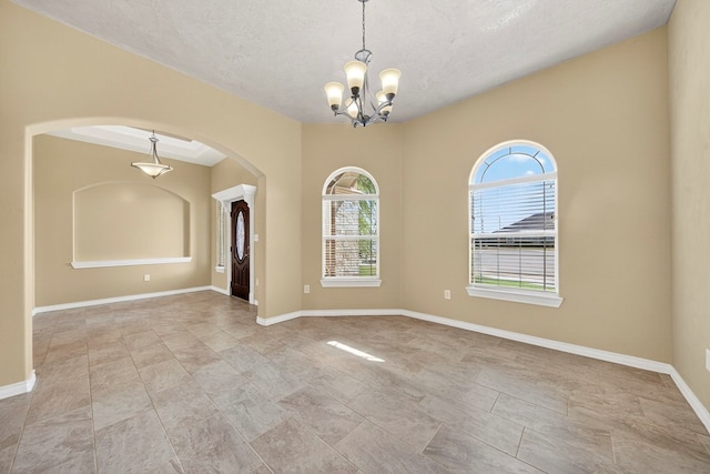 14 Da Vinci Ct, Odessa, TX 79765 - spare room with arched walkways, a chandelier, a textured ceiling, and baseboards