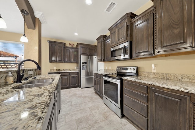 14 Da Vinci Ct, Odessa, TX 79765 - kitchen with appliances with stainless steel finishes, a sink, dark brown cabinetry, light stone counters, and decorative light fixtures