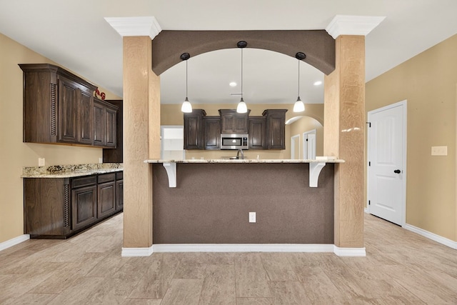 14 Da Vinci Ct, Odessa, TX 79765 - kitchen with stainless steel microwave, a breakfast bar area, and dark brown cabinets