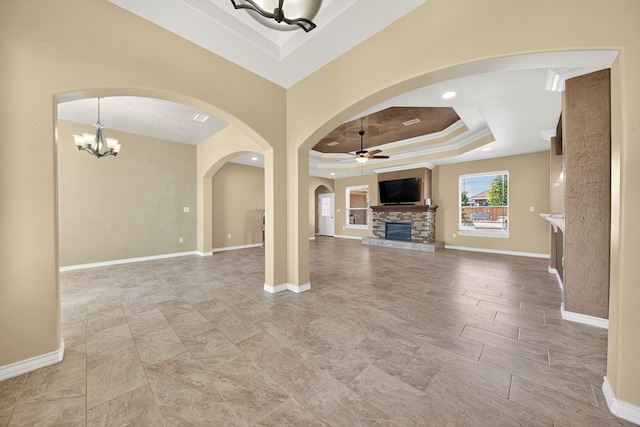 14 Da Vinci Ct, Odessa, TX 79765 - unfurnished living room featuring a raised ceiling, ceiling fan, a stone fireplace, a chandelier, and baseboards