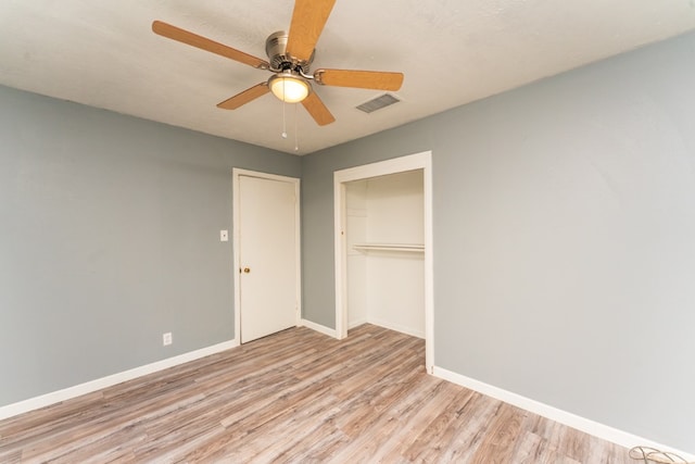 unfurnished bedroom featuring light wood-style flooring, a ceiling fan, baseboards, visible vents, and a closet