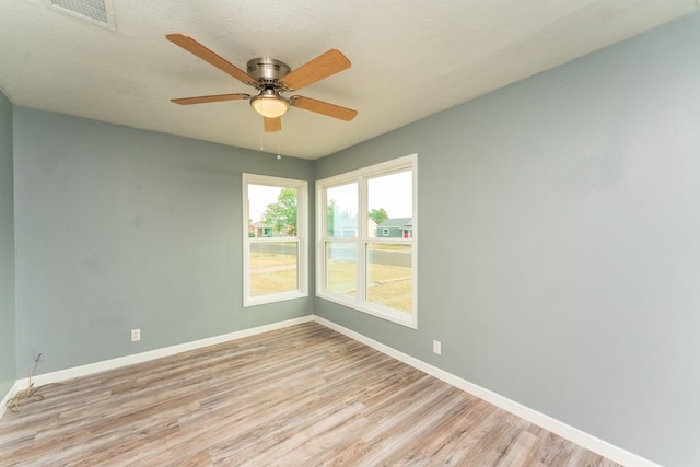 unfurnished room featuring a ceiling fan, baseboards, visible vents, and light wood-type flooring