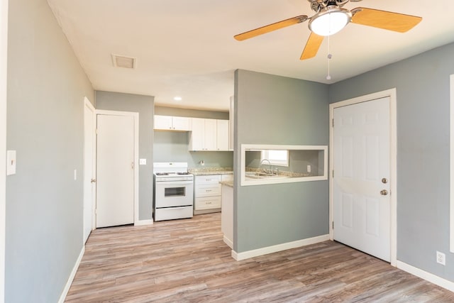 kitchen with light wood-style floors, white gas range, white cabinetry, baseboards, and visible vents